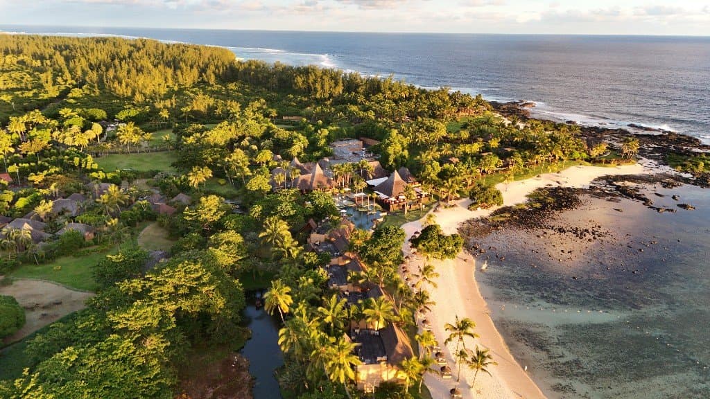 Vue aérienne d’un resort tropical en bord de mer, plage blanche et lagon turquoise