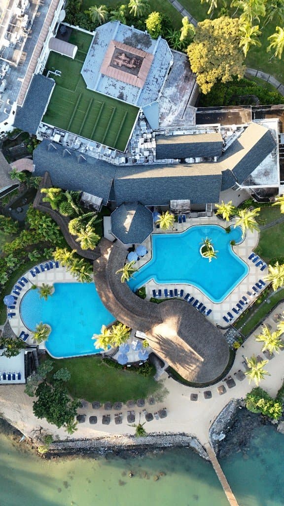 Vue aérienne d’un resort avec deux piscines, palmiers et plage
