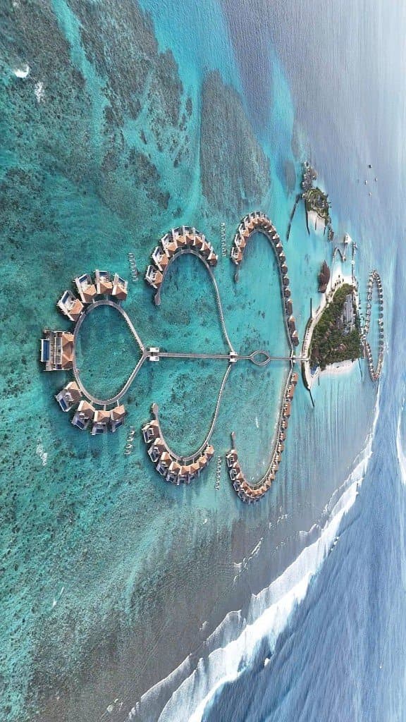 Villas sur l’eau en formations circulaires, lagon turquoise vu du drone