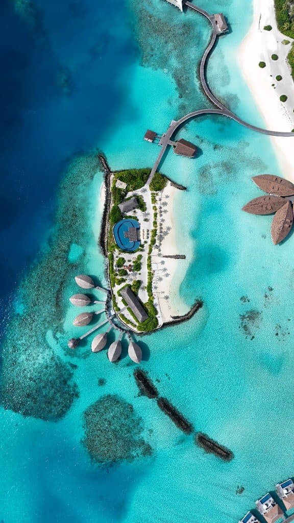 Passerelles courbes et bungalows sur un lagon turquoise, vue drone