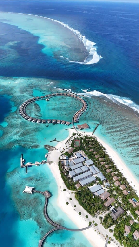 Île et villas sur l’eau en cercle, lagon et récif vus du drone